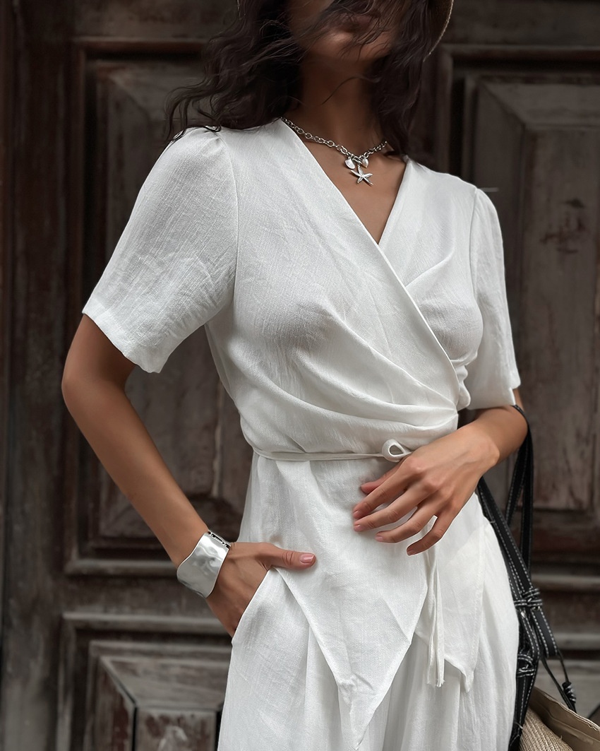 Completo da donna composto da top a portafoglio bianco e pantaloni a gamba larga.