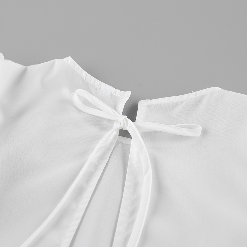 Chemisier élégant à manches bouffantes et volants, orné d'un lien au dos.